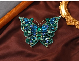 Close-up of vintage butterfly brooch with blue and green rhinestones on silk background
