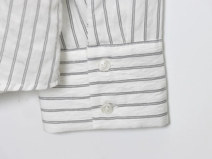 Close-up of striped cotton shirt sleeve featuring fine black lines and white buttons