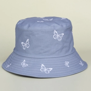 Detailed close-up of white butterfly embroidery on a light blue cotton bucket hat