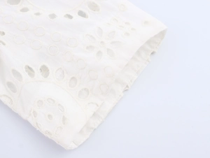 Close-up of intricate floral embroidery and cut-out details on a white cotton dress sleeve