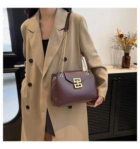 Detail of dark burgundy leather tote bag with gold chain strap and elegant metallic buckle