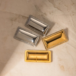 Macro shot of rectangular 18k gold and silver earrings with crystal pave on marble surface