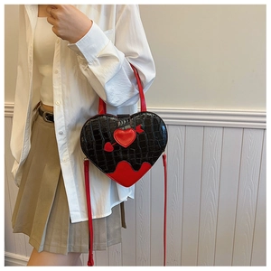 Detail view of heart-shaped crossbody bag with red arrow motif and crocodile texture