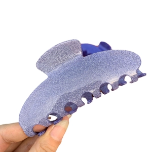 Glittery purple acetate hair claw clip with seven teeth shown in a hand-held view