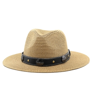 Macro detail of straw fedora hat featuring black leather band with vintage metal ornaments