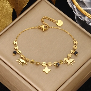 Close-up of golden stainless steel bracelet featuring sunburst and petal charms with black beads