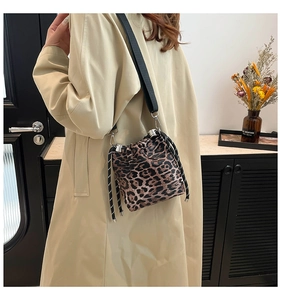 Borsa a secchiello leopardata con coulisse e tracolla larga indossata da una modella