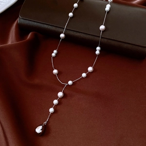 Detail of French vintage pearl Y-necklace with silver water drop pendant on brown satin