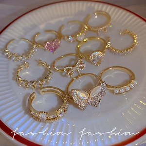 Elegant gold butterfly rings set with pearls and pink heart stones on ceramic tray