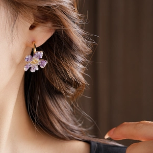 Close-up of a vintage purple flower earring with a yellow center on a model side profile