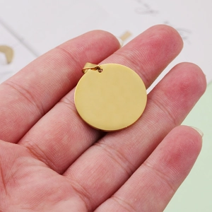 Polished golden stainless steel round pet tag pendant held by hand for engraving