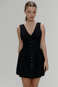Détail d'une robe noire à col en V avec broderies ajourées et boutons sur le devant