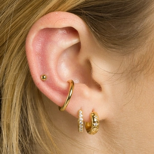Close-up of gold ear cuff and star engraved hoop earrings with micro zircon studs