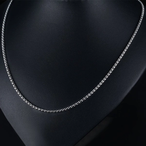 Gros plan d'un collier chaîne box en acier inoxydable argenté sur un buste de mannequin noir