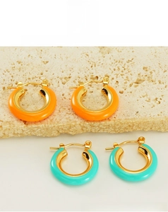 Detail view of orange and turquoise enamel hoop earrings with gold-plated finish