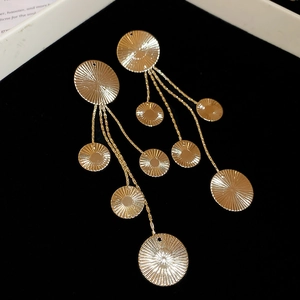 Macro detail of golden tassel earrings with circular texture on black velvet background