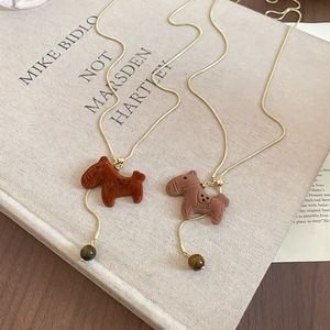 Detailed view of flocked pony pendant with tiger eye bead on golden chain necklace