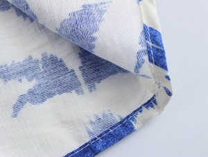 Nahaufnahme von weißem Stoff mit blauen Mustern, Textur und feiner Verarbeitung