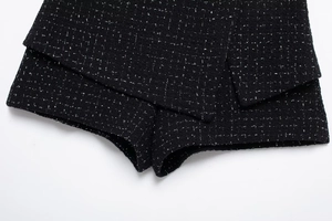 Gros plan détaillé sur la texture du tweed noir et le design superposé du short assorti