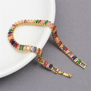 Detailed close-up of rainbow crystal bracelet with gold plating on white ceramic surface
