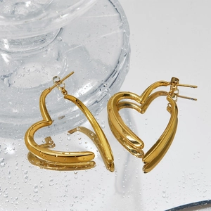 Golden stainless steel heart-shaped earrings on a reflective surface with water drops