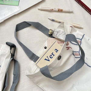 Detalle del bolso de lona blanca con cierre de botón y estampado de oso y conejo