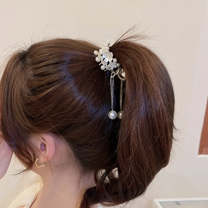 Detail showing elegant flower hair claw clip with pearl tassels on ponytail hairstyle