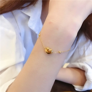 Detail eines goldenen Herzarmbands mit Perlen am Handgelenk für ein elegantes Styling