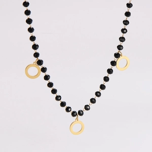 Detail of minimalist necklace with black faceted beads and three golden round pendants