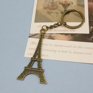 Macro view of a vintage bronze Eiffel Tower keychain on a decorative poetic card
