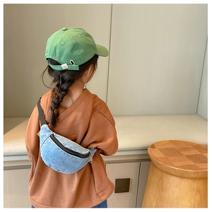 Detail of light blue denim waist bag with adjustable black strap worn by a child