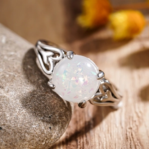 Macro shot of silver ring with round white opal and heart-shaped cutout band design