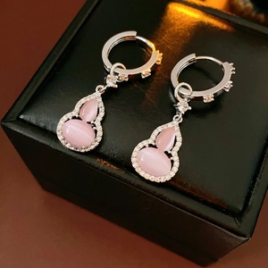 Macro view of pink opal gourd earrings with zircons on a luxury black jewelry box