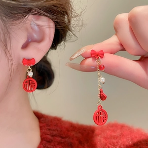 Detail of red bow earring with gold chain, pearl and fortune pendant for New Year