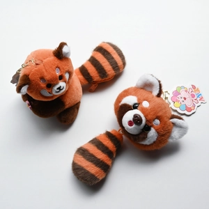 Detailed view of two cute plush red panda keychains with striped tails and golden clips
