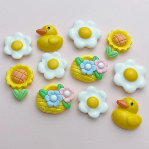 Flat lay of colorful resin charms including ducks, flowers, and baskets for DIY crafts