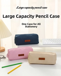 Three canvas pencil cases in navy, pink, and beige with leather basic label on desk