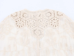 Detail of beige crochet neckline with floral embroidery on bohemian style knit cardigan