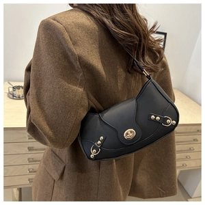 Detail of black leather crescent underarm bag with gold lock and decorative studs on model
