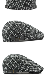 Detail van vintage tweed platte pet met zwart-wit textuur en zijdelingse gespdetail
