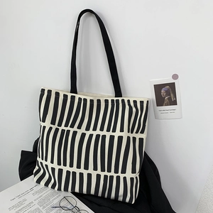 Minimalist black and white striped canvas tote bag hanging on a clean white wall