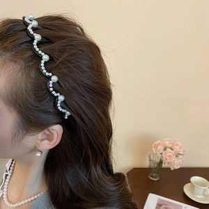 Macro detail of the wave-shaped pearl headband on model showing elegant styling