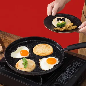 Four-hole non-stick frying pan with heart and round molds on a portable stove