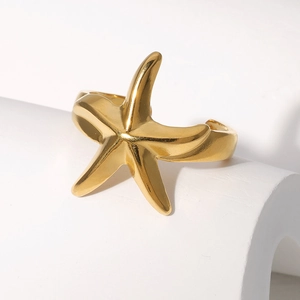 Vue détaillée d'une bague étoile de mer dorée sur un support blanc minimaliste