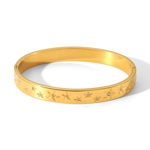 Macro detail of a gold stainless steel bangle featuring star charms with inset crystals