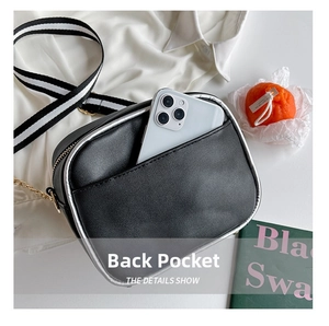 Detail show of the back pocket on a black pebble leather crossbody bag with striped strap