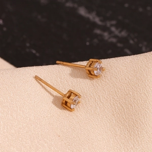 Macro shot of gold-plated four-prong stud earring featuring a clear round zircon stone