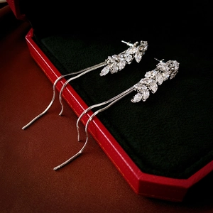 Macro shot of silver tassel earrings with wheat-shaped zircons in a red velvet jewelry box