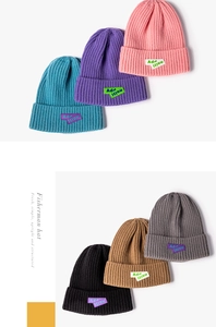 Close-up of ribbed knit beanies in various colors with decorative brand labels