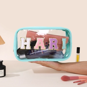 Detail of transparent PVC makeup bag with HARI glitter letters and turquoise trim